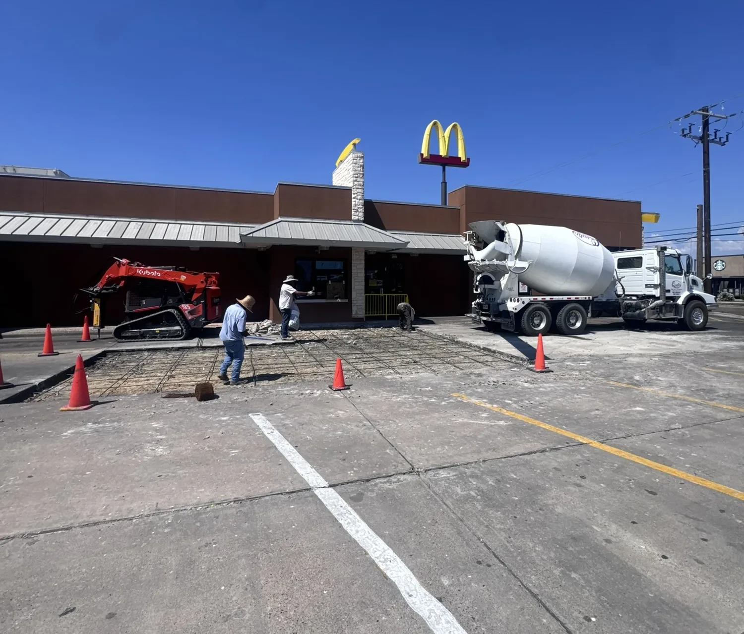 Lucky's Concrete crew pouring a commercial parking lot at a McDonald's with rebar grid and a concrete mixer truck on site